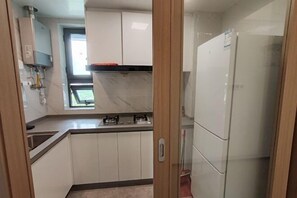 Una cocina compacta con armarios blancos, estufa integrada y refrigerador.