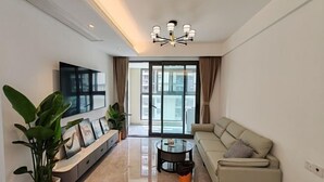 Un salon moderne avec un canapé, une table basse, un téléviseur et de grandes fenêtres.