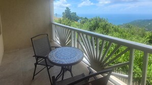 A balcony with a table and chairs, offering a view of a lush landscape and distant mountains. - Sage Mountain Skyway 3 (Road Town)