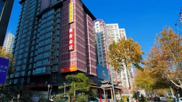 A multi-story building with a prominent red and black facade, surrounded by trees and parked bicycles.