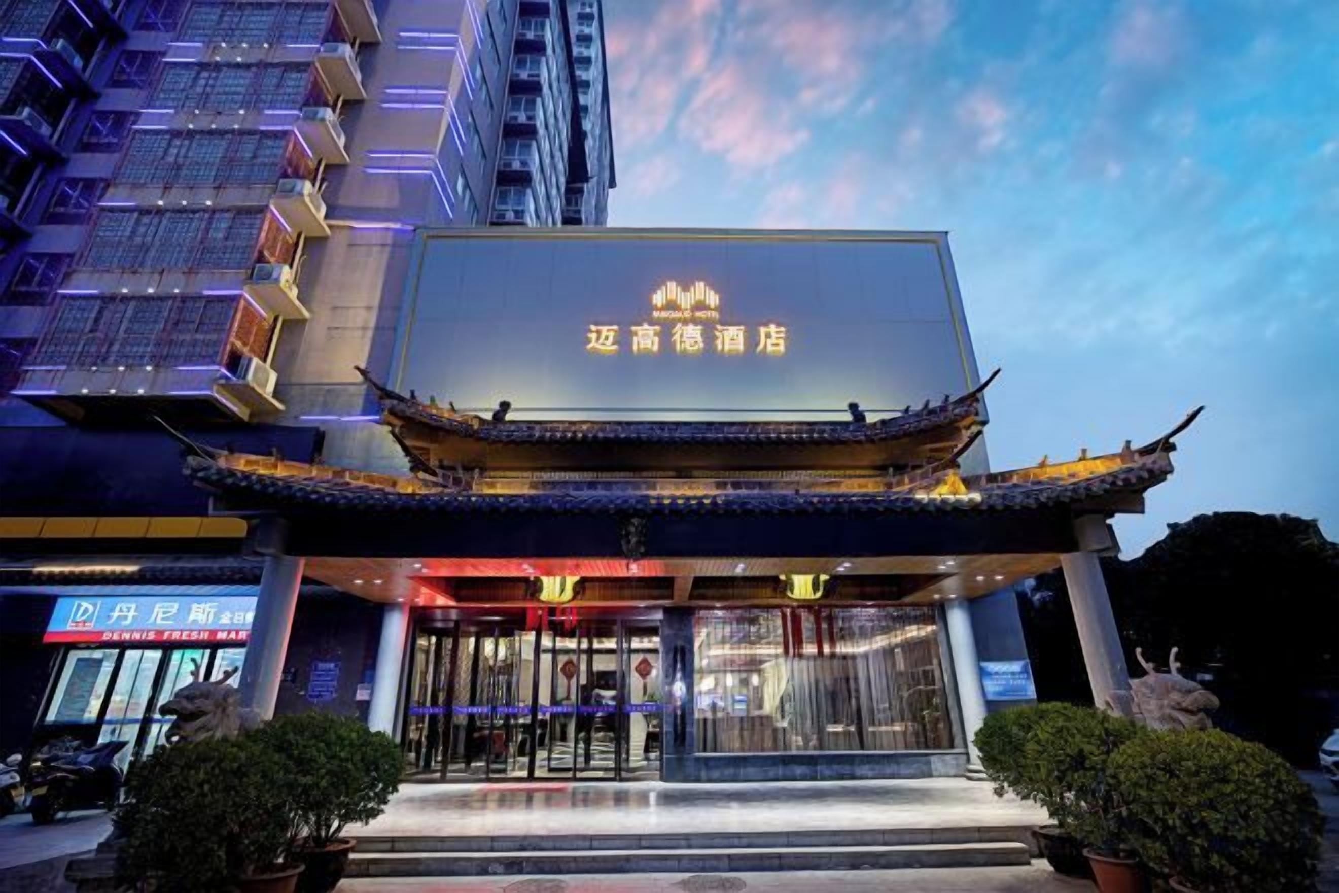 A hotel with a traditional architectural style, featuring a prominent entrance with a tiled roof and a large illuminated sign.