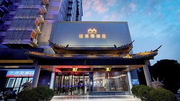 A hotel with a traditional architectural style, featuring a prominent entrance with a tiled roof and a large illuminated sign.