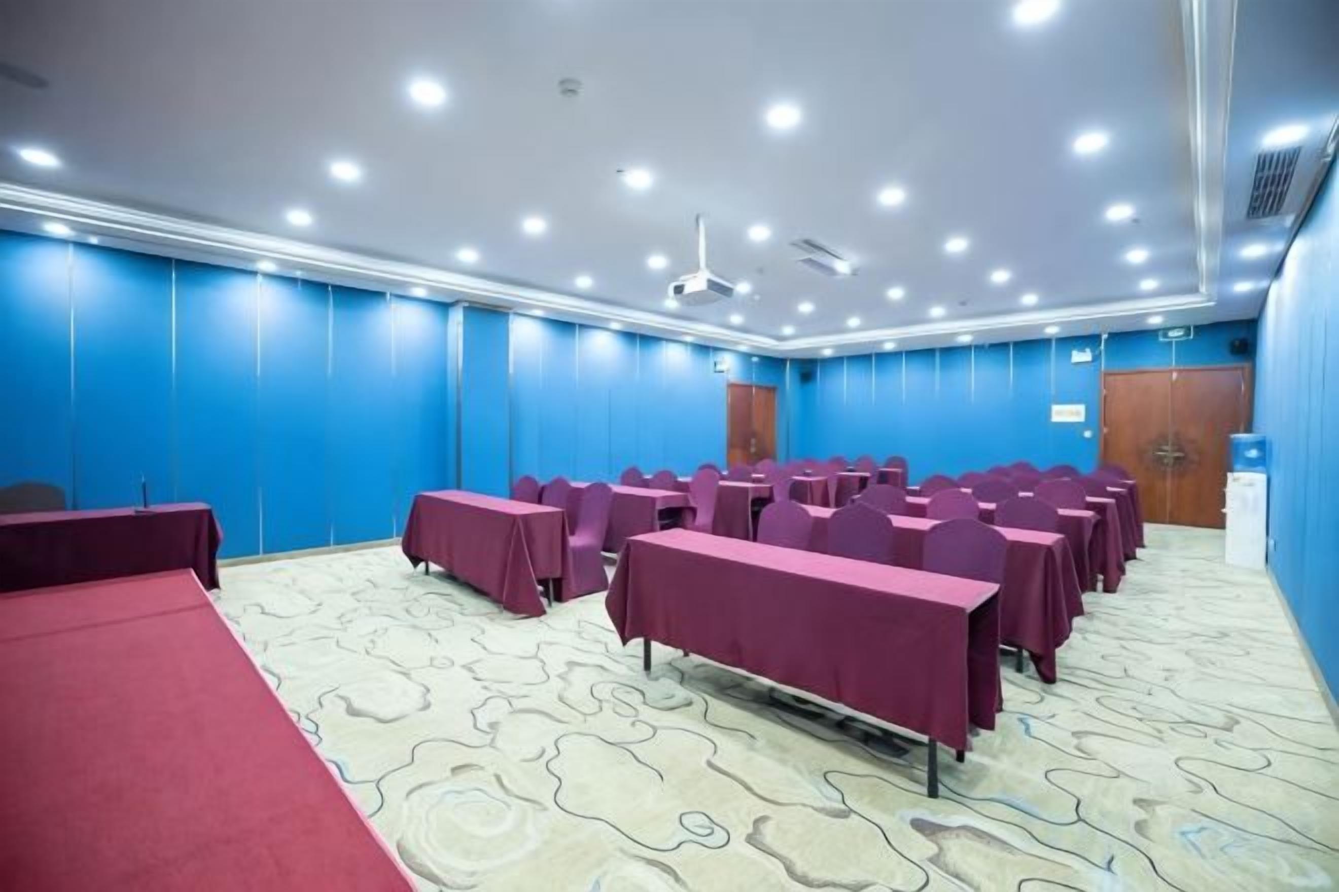 A conference room with tables and chairs, a carpeted floor, and a blue wall.