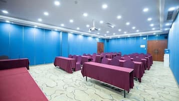 A conference room with tables and chairs, a carpeted floor, and a blue wall.