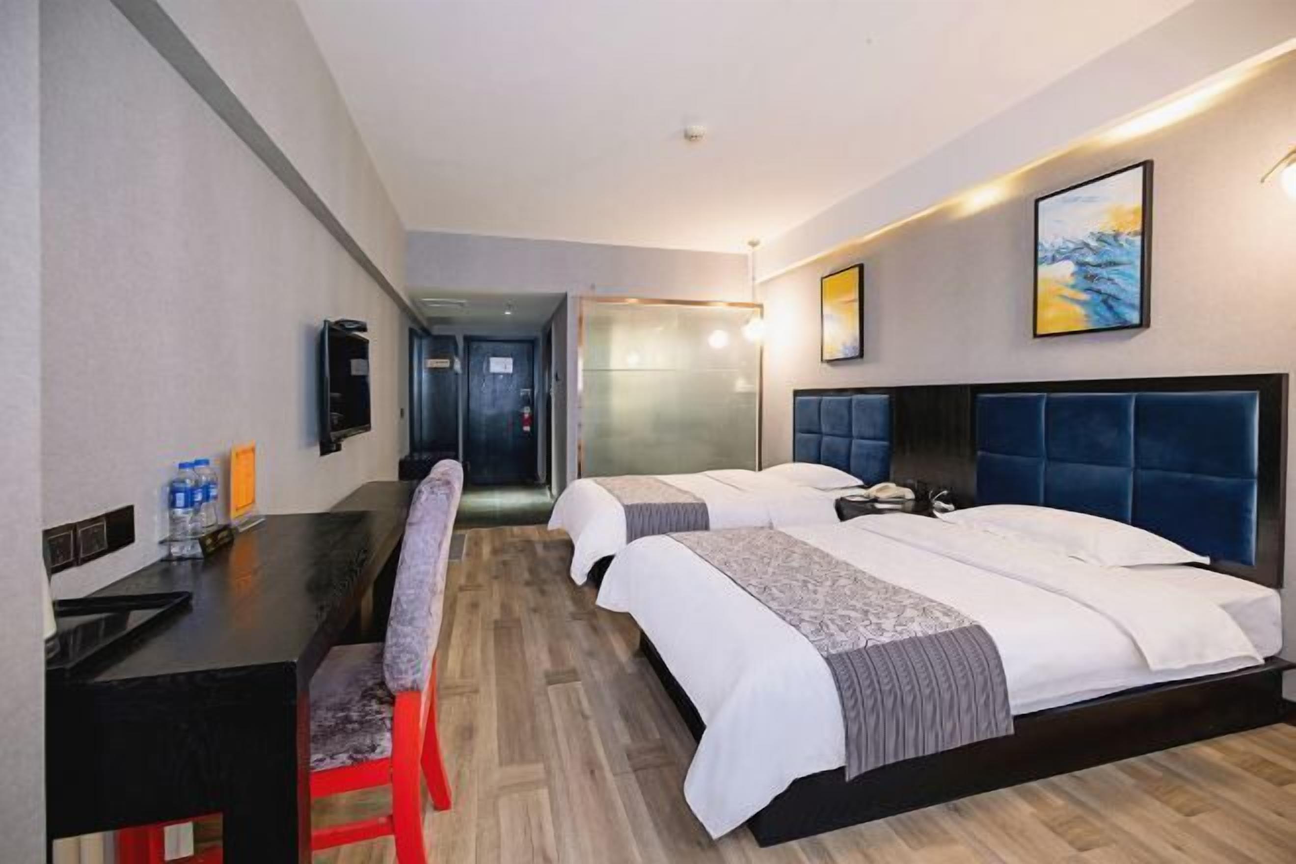 A hotel room with two beds, a desk, and a chair.