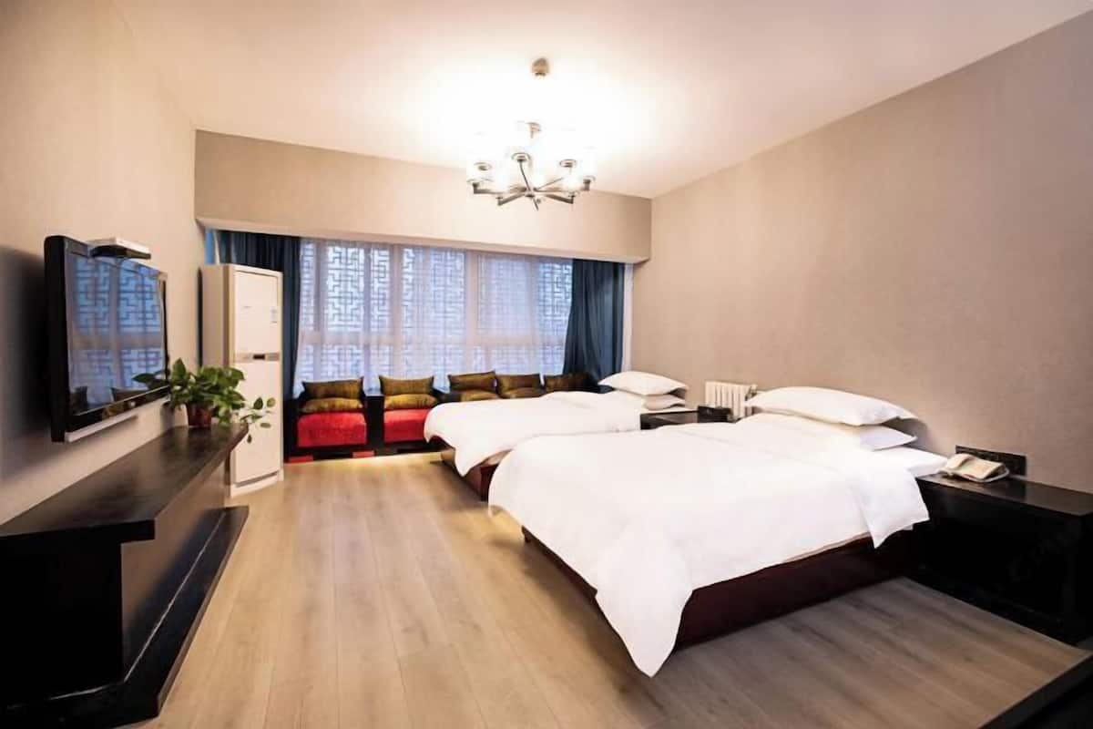 Een hotelkamer met een groot bed, een televisie, een bureau en een raam met gordijnen.