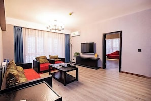 Uma sala de estar moderna com sofá, mesa de centro, televisão e uma poltrona vermelha.