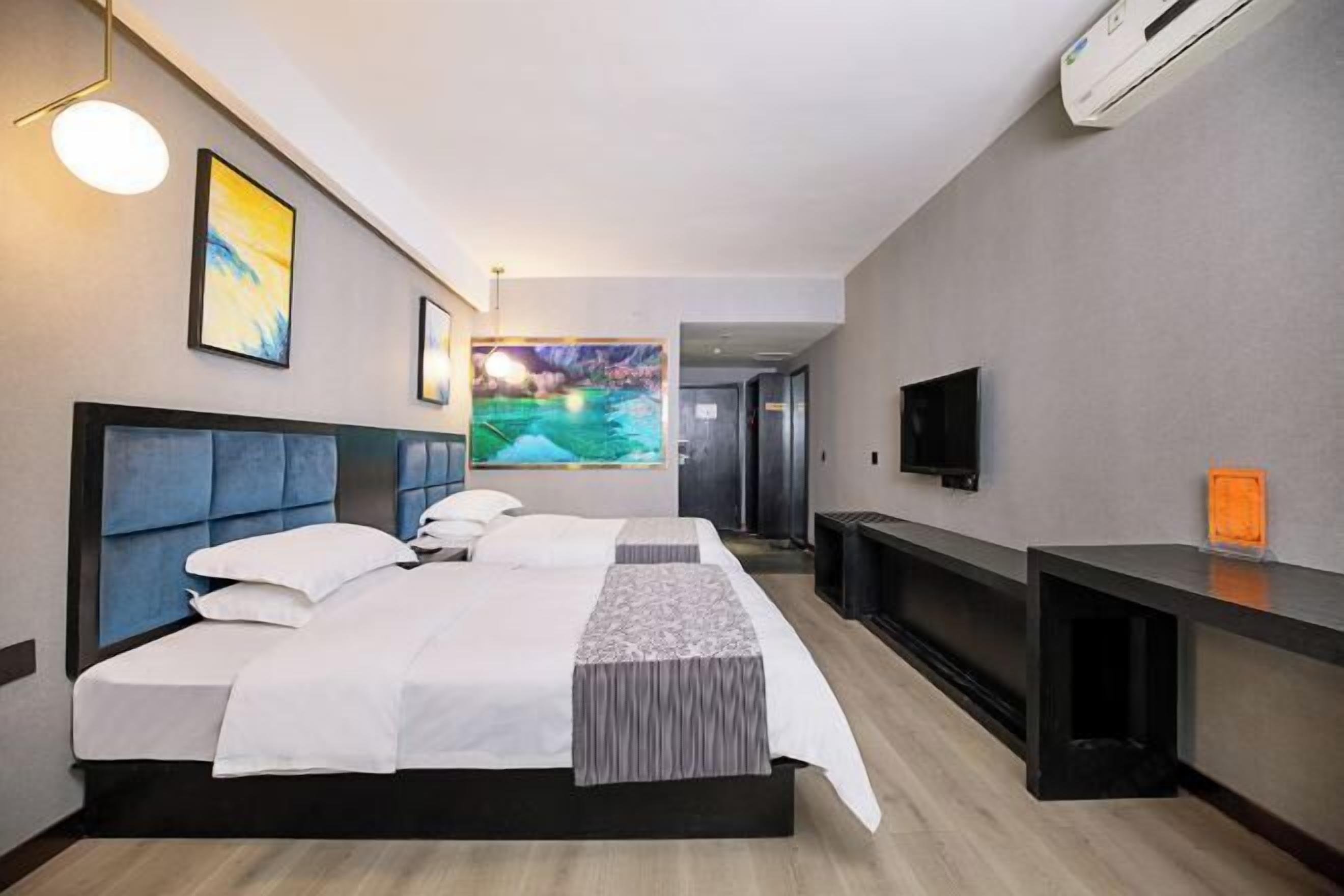 Una habitación de hotel con cama, televisión, escritorio y obras de arte en las paredes.