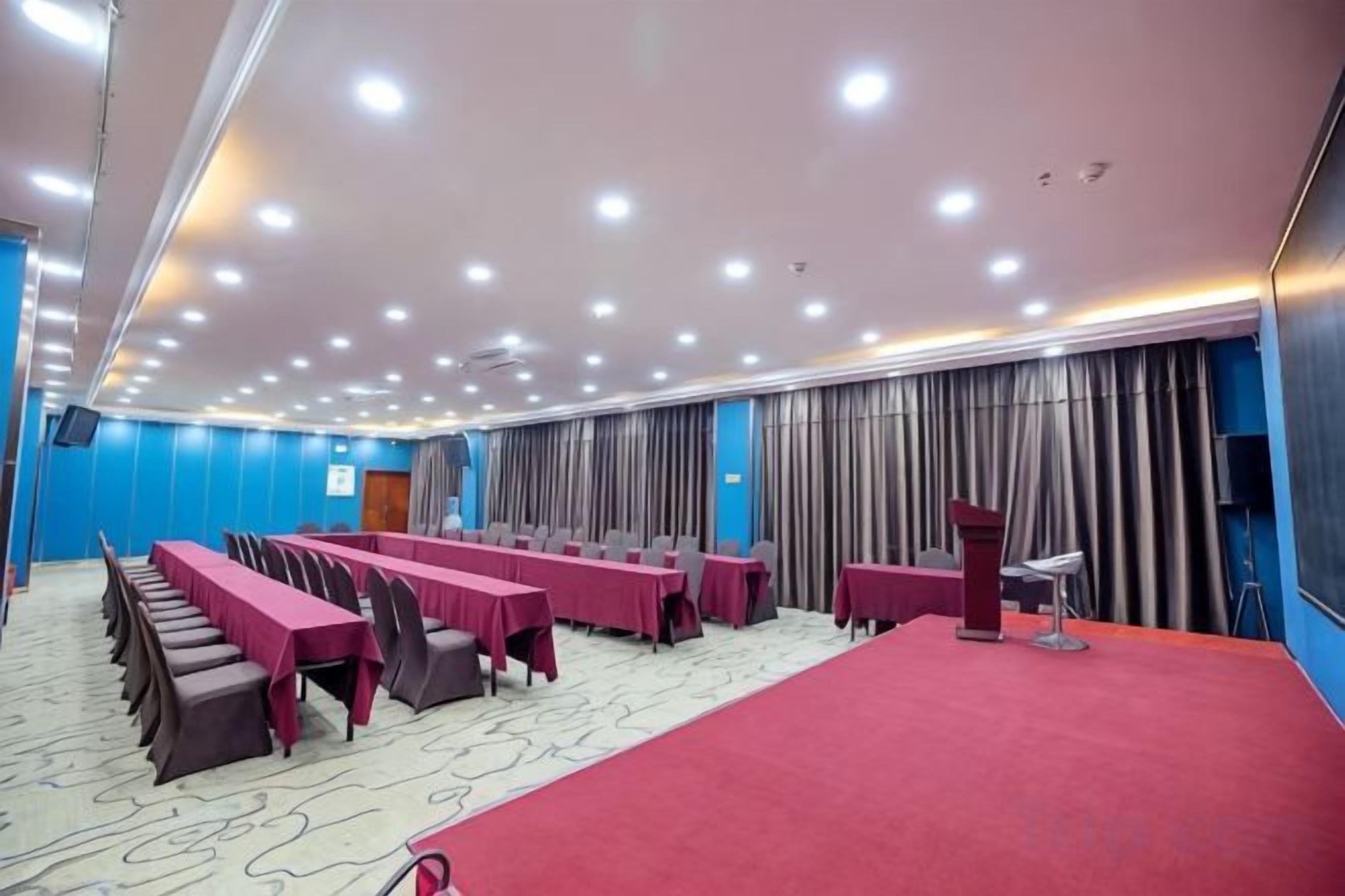 Une salle de conférence dotée de plusieurs tables, d’un pupitre et d’un tapis rouge.