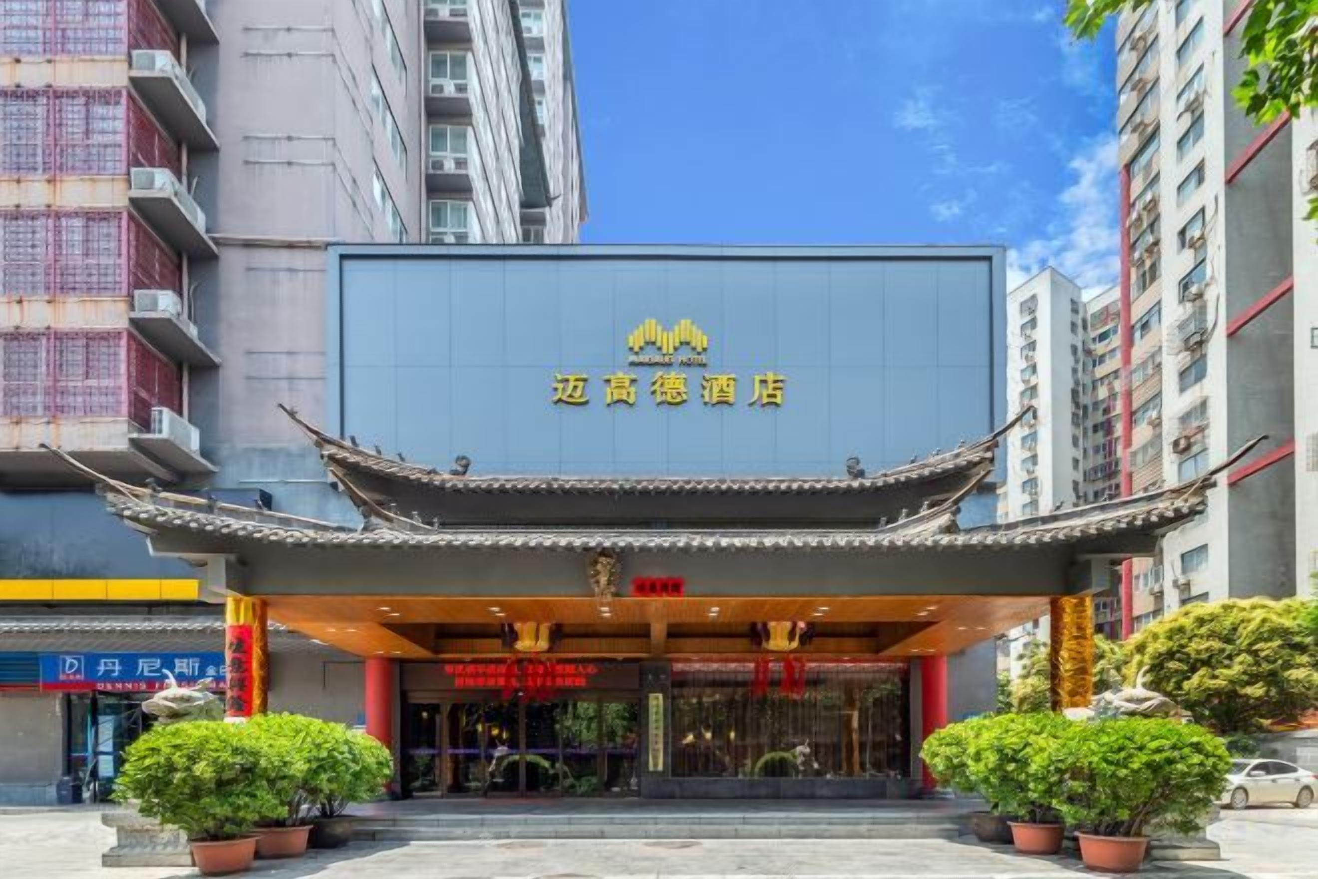 A hotel with a traditional Chinese architectural entrance, a clear blue sky, and potted plants in front.