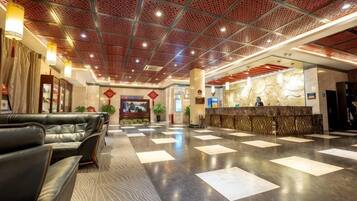 A hotel lobby with a reception desk, seating area, and a patterned floor.