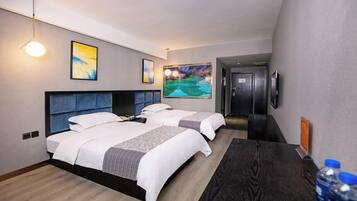 A hotel room with two beds, a desk, a TV, and artwork on the walls.