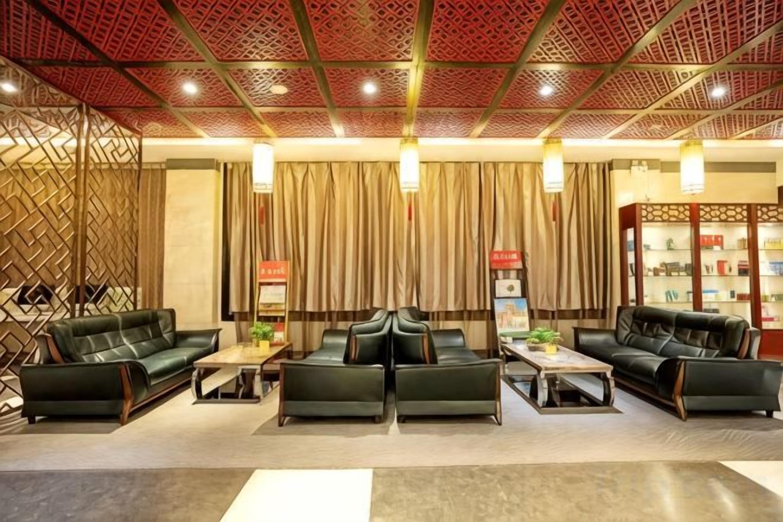 A hotel lobby with leather sofas, a coffee table, a bookshelf, and a decorative wall.
