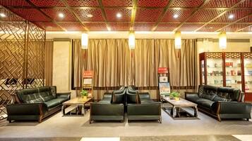 A hotel lobby with leather sofas, a coffee table, a bookshelf, and a decorative wall.