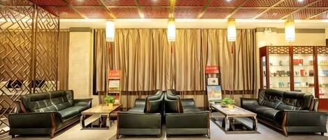 Eine Hotelhalle mit Ledersofas, einem Couchtisch, einem Bücherregal und einer Wanddekoration.