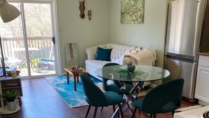 A modern kitchen with a glass dining table, green chairs, a white sofa, and a stainless steel refrigerator. - Cozy one bedroom apartment  (Peterborough)