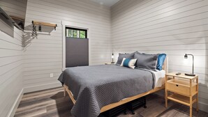 A bedroom with a bed, bedside table, and a window with blinds. - Secluded Getaway,  Centrally located newly built barndo, AC & WIFI (Elmira)