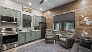 A modern kitchen with stainless steel appliances, light green cabinets, and a wooden accent wall. - Secluded Getaway,  Centrally located newly built barndo, AC & WIFI (Elmira)