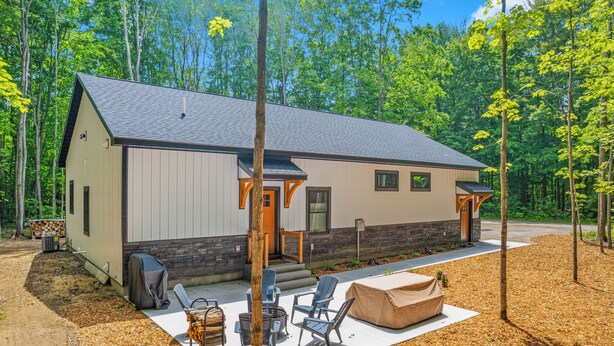 A modern cabin with a covered patio, outdoor seating, and a fire pit. - Secluded Getaway,  Centrally located newly built barndo, AC & WIFI (Elmira)