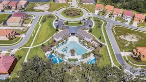 An aerial view of a residential area with a central swimming pool surrounded by houses, roads, and greenery. - Last Minute Disney Getaway! Luxury Villa with Private Pool. Book Now! #65541 (Orlando)
