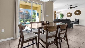 A spacious dining area with a large table and chairs, a ceiling fan, and a view of a pool through glass doors. - Last Minute Disney Getaway! Luxury Villa with Private Pool. Book Now! #65541 (Orlando)