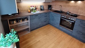 A modern kitchen with grey cabinets, a wooden countertop, a built-in oven, and a sink.