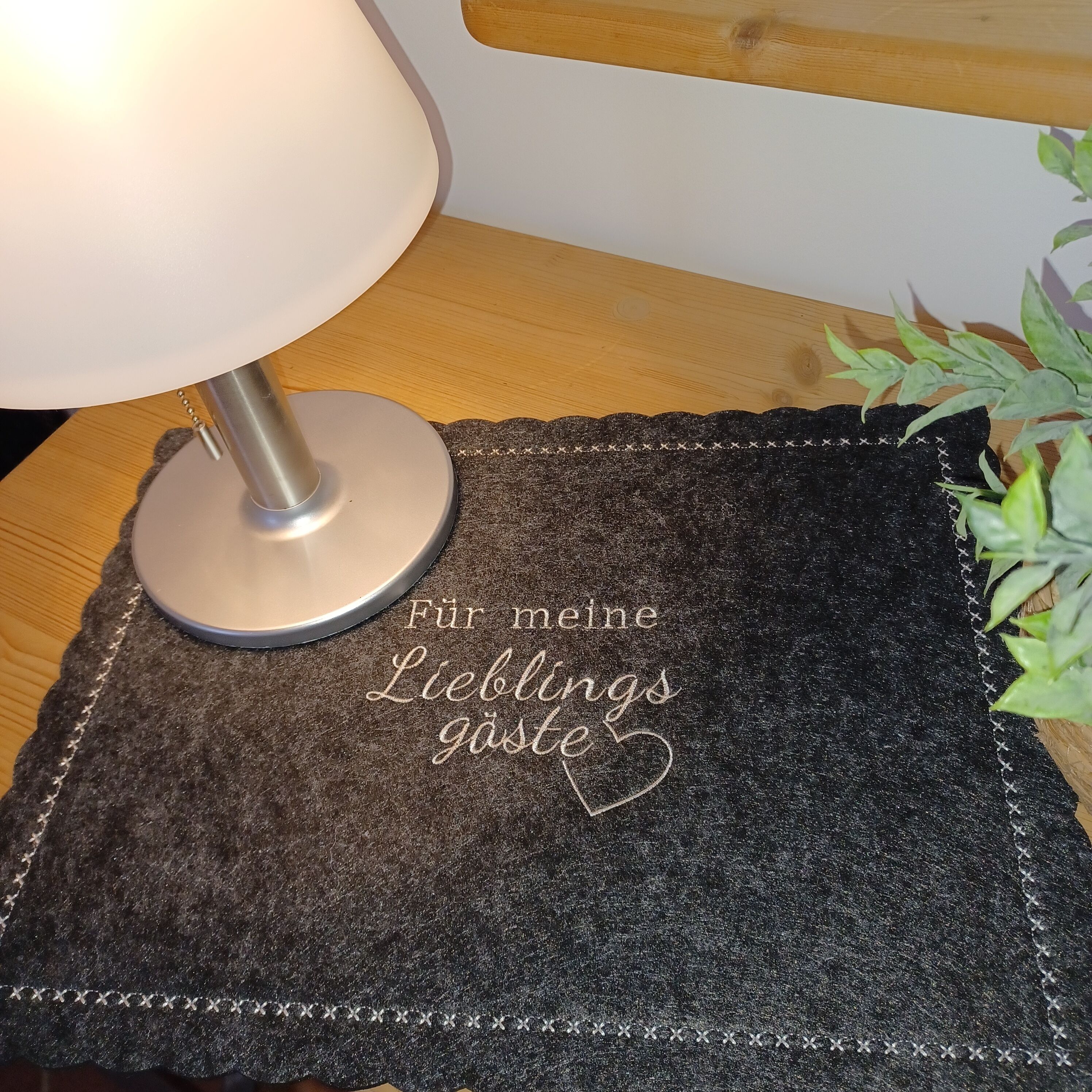 A table with a lamp and a placemat with a message in German.