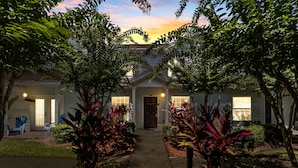 A residential house with a front porch, a driveway, and a well-maintained garden with various plants and shrubs.