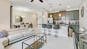 Un salon moderne avec un canapé, une table basse en verre et un ventilateur de plafond.