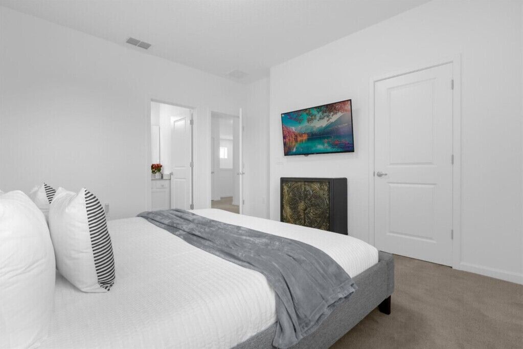 A bedroom with a bed, a painting, and a door.