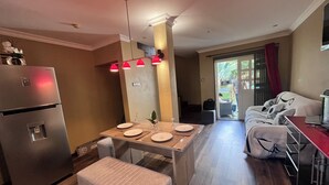 A modern kitchen with a built-in refrigerator, a dining table set with plates and glasses, and a bench. - Charming beach apartment - 5 minutes from Pereybere beach (pereybere)