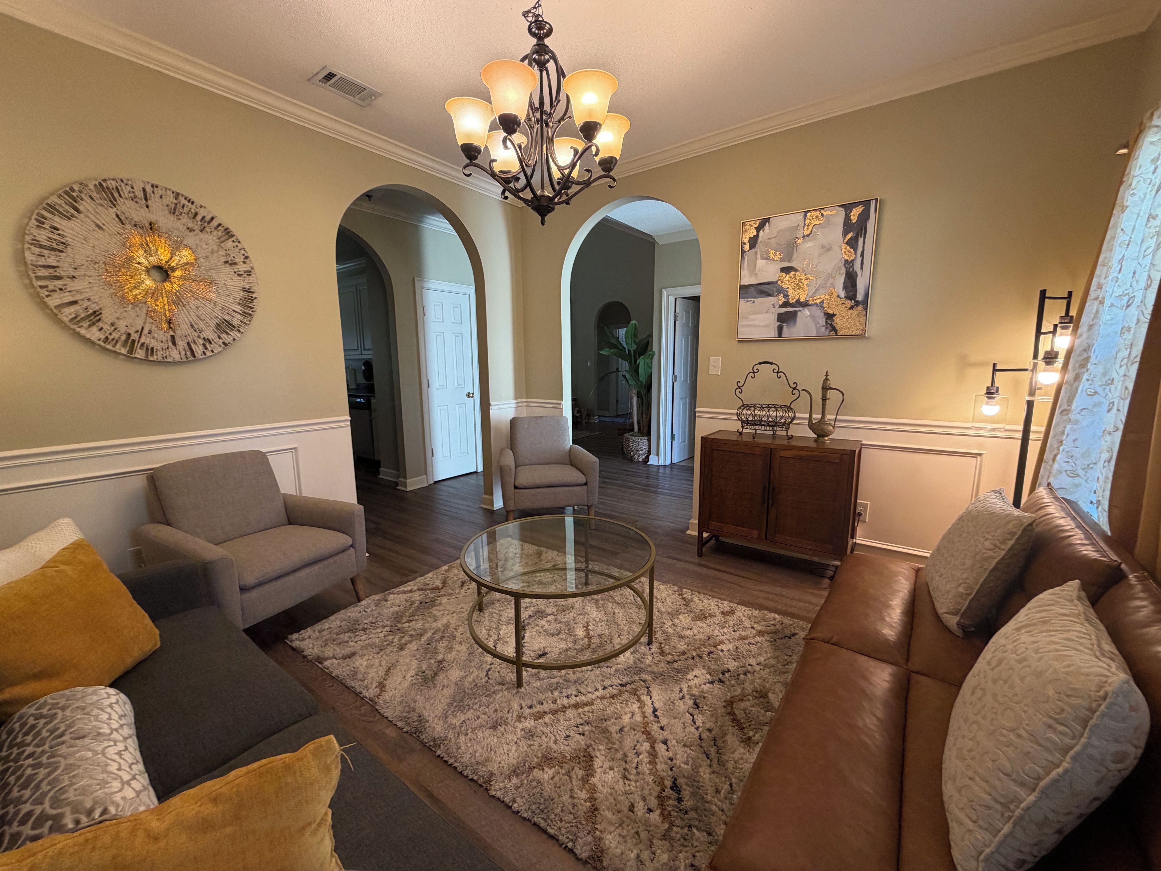 A living room with a fireplace, a chandelier, and a dining area.