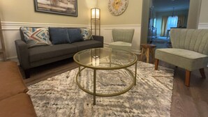 A living room with a sofa, armchairs, a glass coffee table, a rug, a painting, and a clock on the wall. - Lovely 3 bedroom, 2 Bath Home in Lake Park near I-75! (Lake Park)