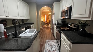 A kitchen with white cabinets, a black countertop, a stainless steel refrigerator, and a microwave. - Lovely 3 bedroom, 2 Bath Home in Lake Park near I-75! (Lake Park)