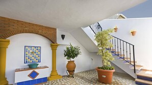 A tiled patio with a staircase, a wall-mounted decorative tile, a potted plant, and a small table with a blue and yellow design. - Villa Fuente by Villa Plus (Frigiliana)