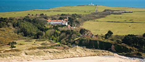 A coastal property with a large house, a lighthouse, and a beach.
