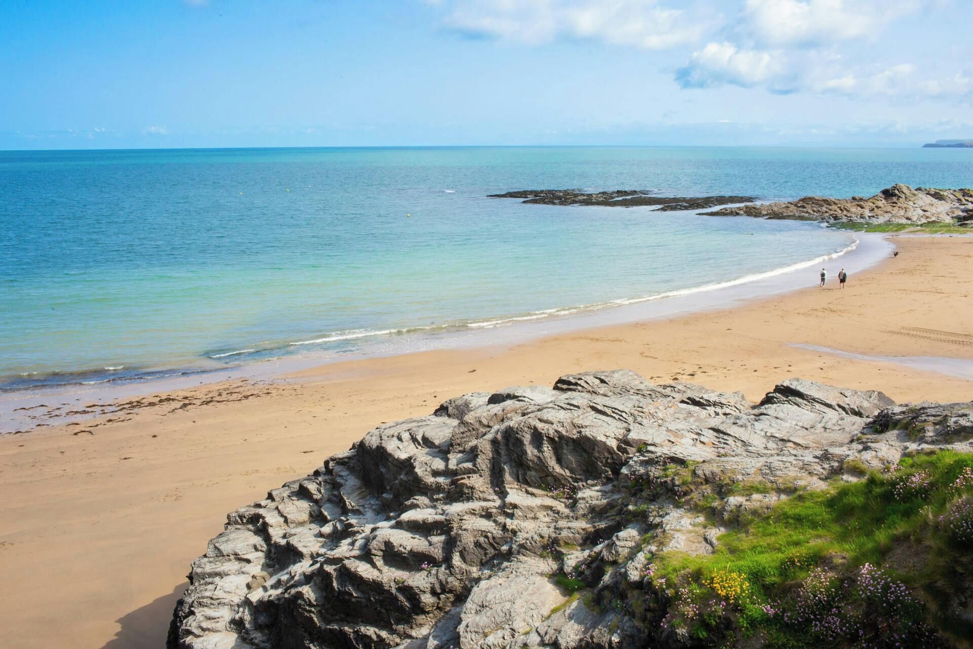 A beach with rocky outcrops and calm waters.
