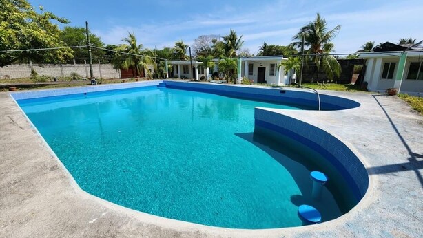 Une piscine rectangulaire dotée d’une partie incurvée, entourée d’une terrasse en béton.