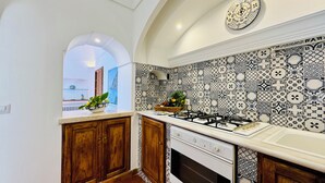 A kitchen with patterned tiles, wooden cabinets, a gas stove, and an oven. - YourHome - La Casa di Chiara (Positano)