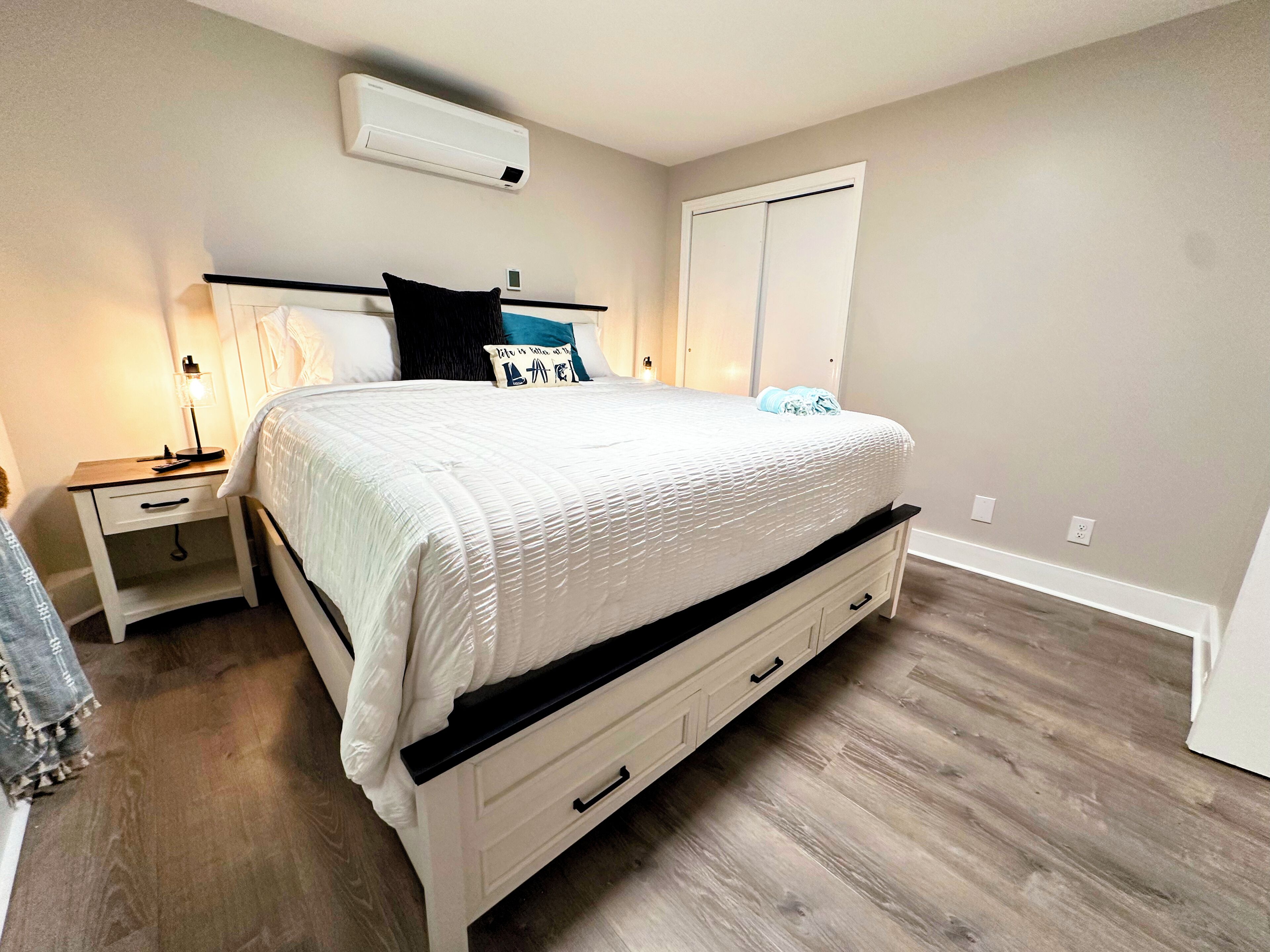 Un dormitorio con cama, mesitas de noche, armario y aire acondicionado.
