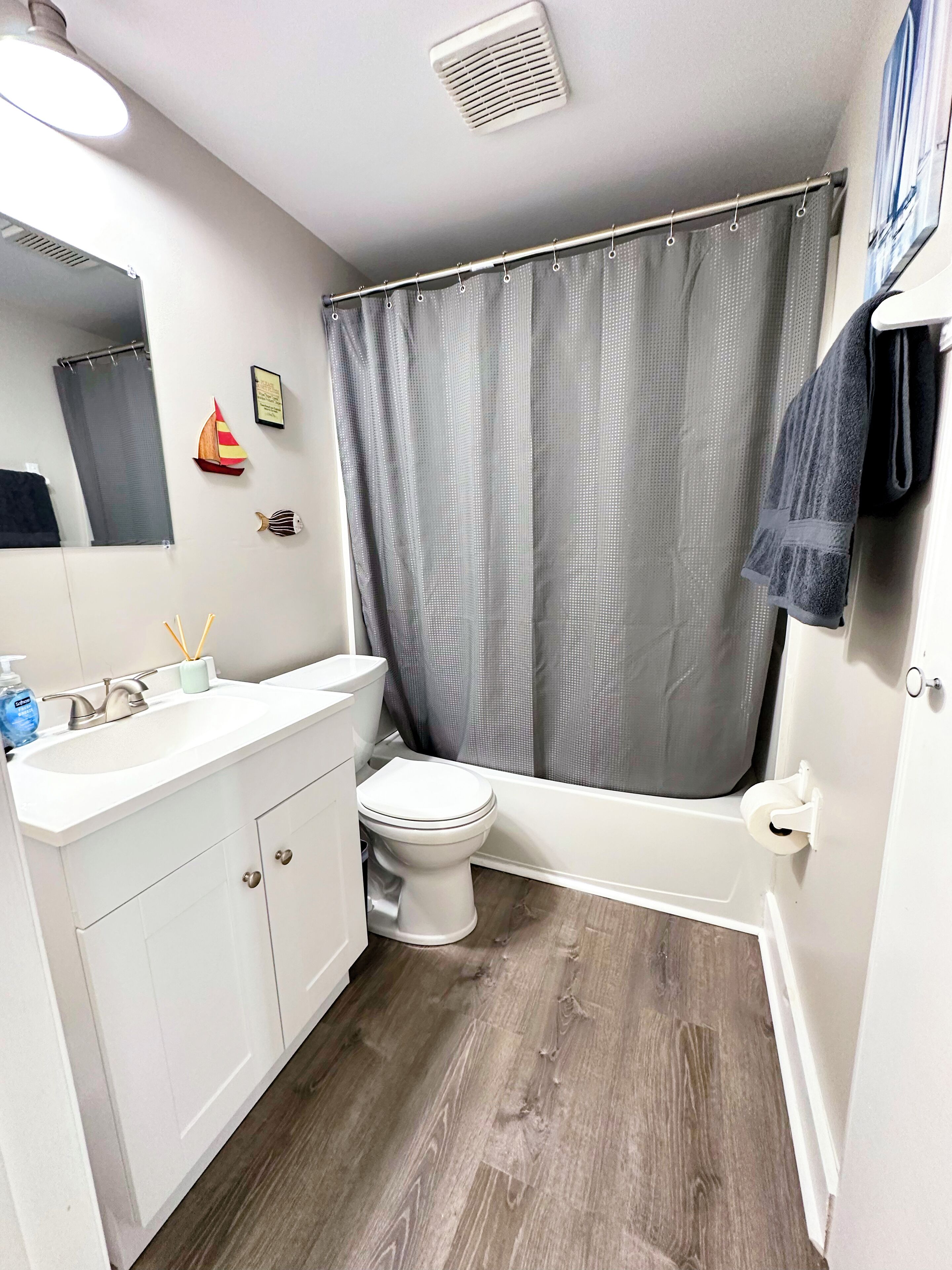 Un baño moderno con tocador blanco, inodoro y cortina de ducha.