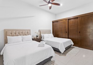 A hotel room with two beds, a wooden wardrobe, a ceiling fan, and a small nightstand with a plant. - Casa Bella Puerto Vallarta (Puerto Vallarta)