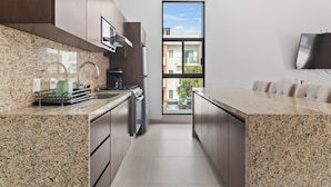 A modern kitchen with granite countertops, stainless steel appliances, and a large window offering a view of the outside. - Casa Bella Puerto Vallarta (Puerto Vallarta)