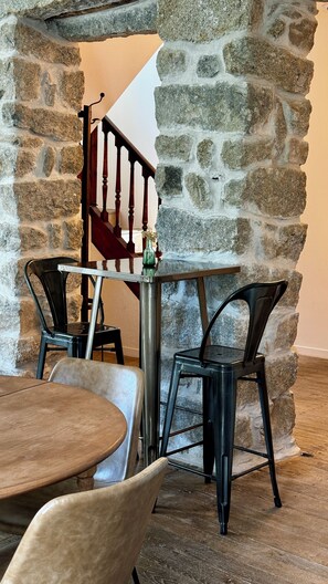 Cozy space with a rustic stone wall, wooden staircase, and a round table with two chairs.