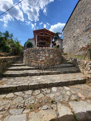 Staircase leads to a rustic structure against a stone wall.