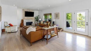 A spacious living room with a fireplace, a sofa, a coffee table, and a television. - Charming Lakeside Escape w/ Large Deck & Firepit! (Clarkson)