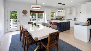 A modern kitchen with white cabinets, a central island, and pendant lighting. - Charming Lakeside Escape w/ Large Deck & Firepit! (Clarkson)
