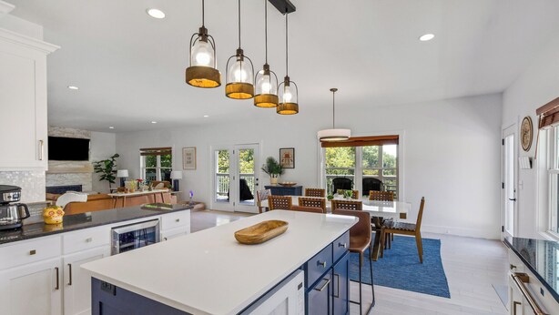A spacious kitchen with a large island, pendant lights, and a dining area with a blue rug. - Charming Lakeside Escape w/ Large Deck & Firepit! (Clarkson)