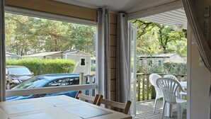 Ein Zimmer mit Tisch und Stühlen, eine Schiebetür zu einer Terrasse im Freien und Blick auf die Umgebung.