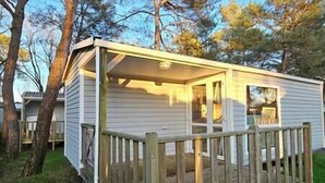 Une petite maison mobile d’un seul étage, dotée d’une terrasse en bois et d’un porche couvert.